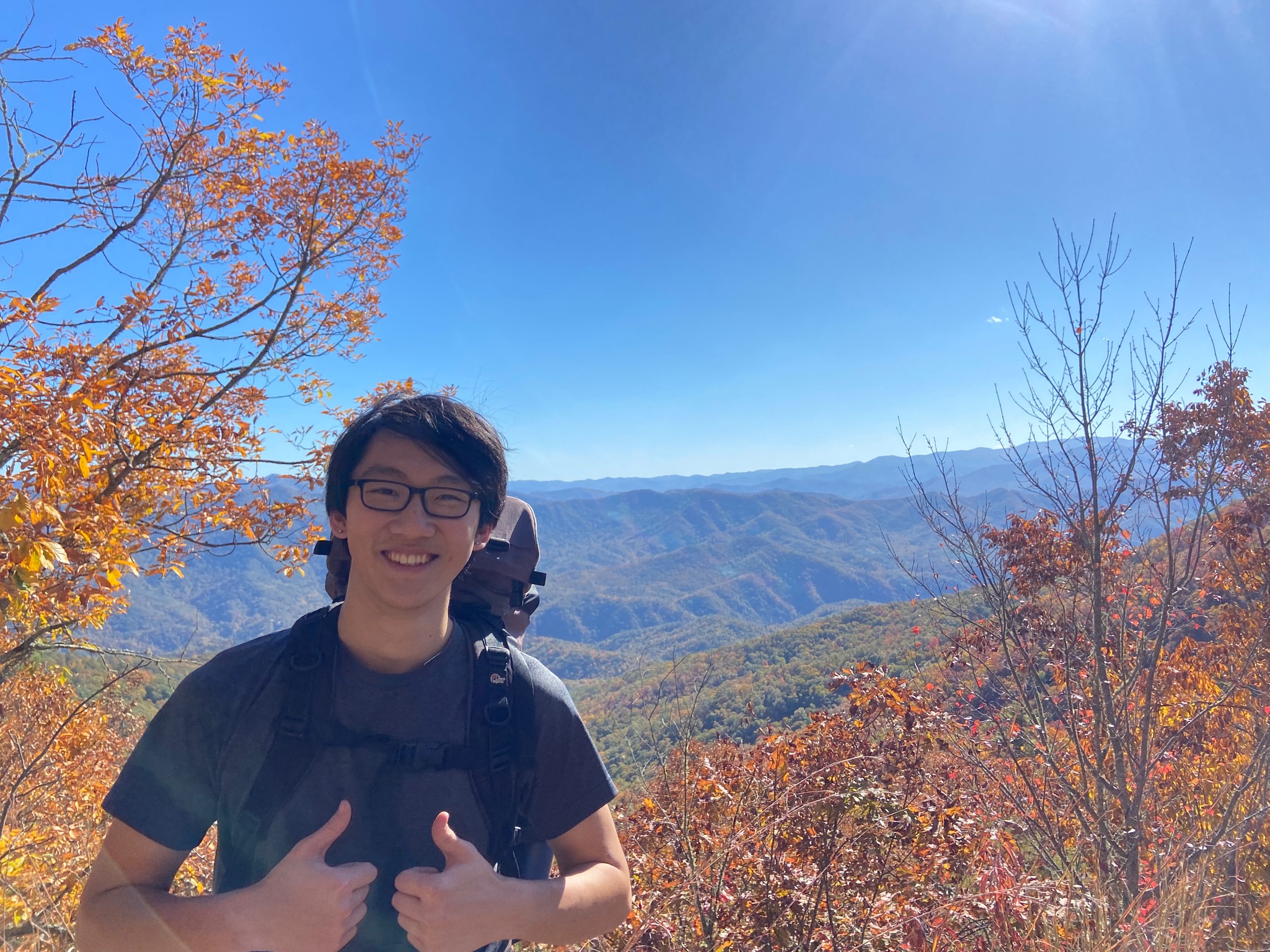 Photo of Tiger backpacking, smiling at the camera with two thumbs up